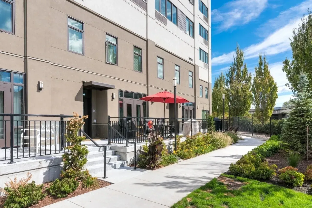 Modern apartment building exterior with a patio area and landscaping.