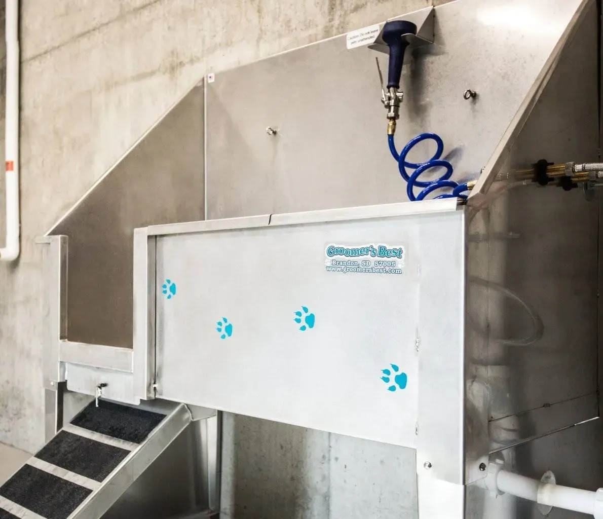 Stainless steel pet washing station with shower hose and paw print decals.