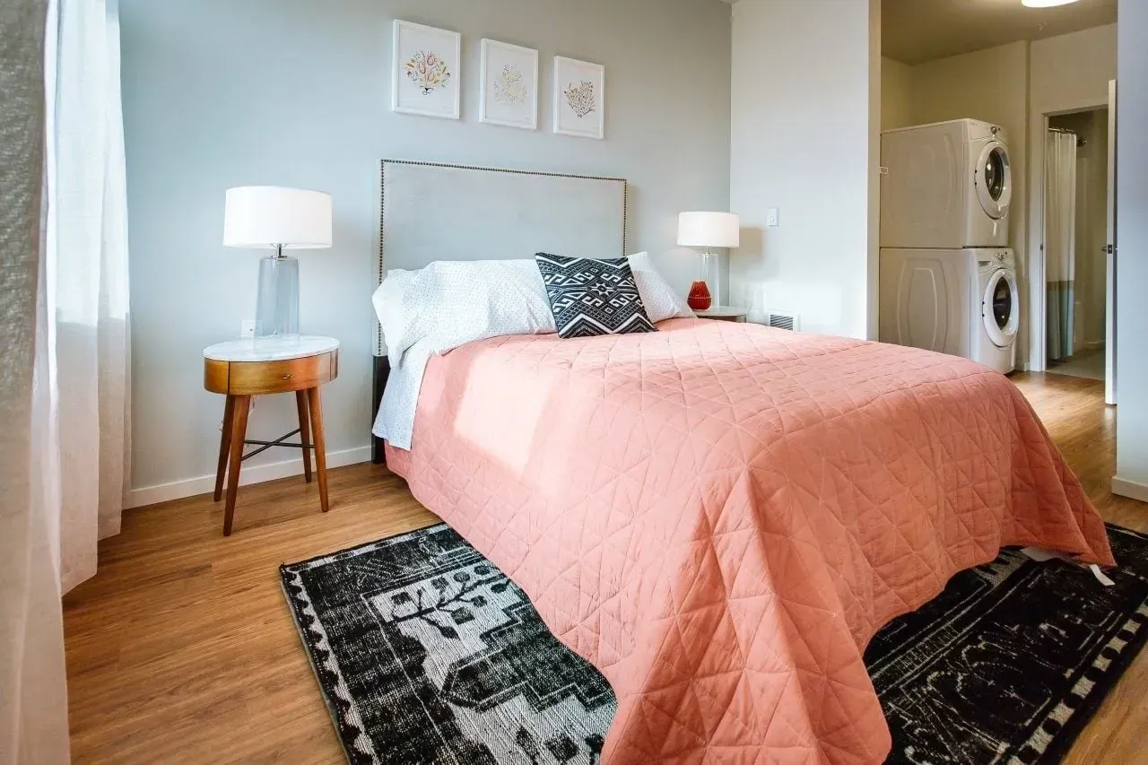 Cozy bedroom with a large bed, nightstands, and a stacked washer/dryer.