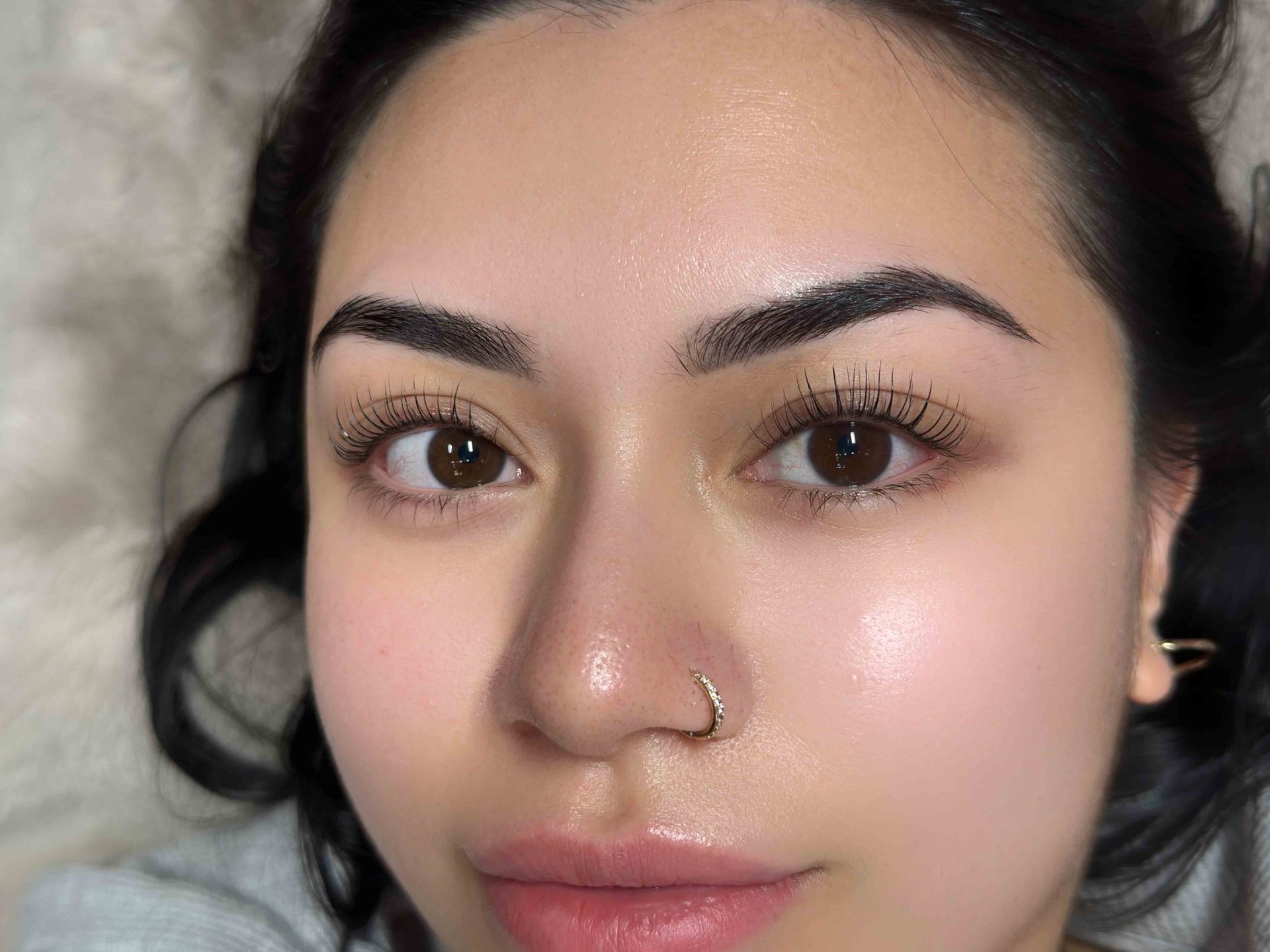 Beauty salon treatment with a technician applying makeup to a client lying on a treatment bed
