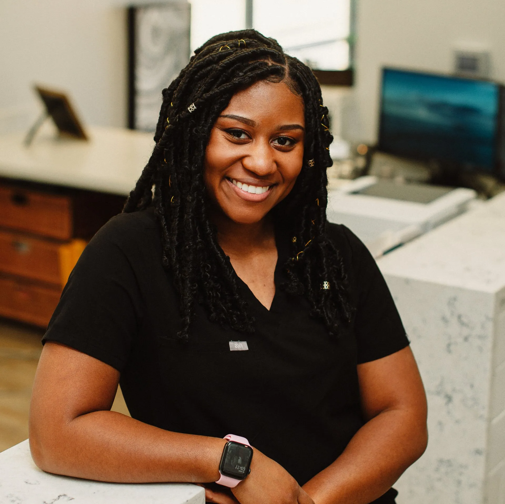 A woman wearing a black shirt and a watch is smiling