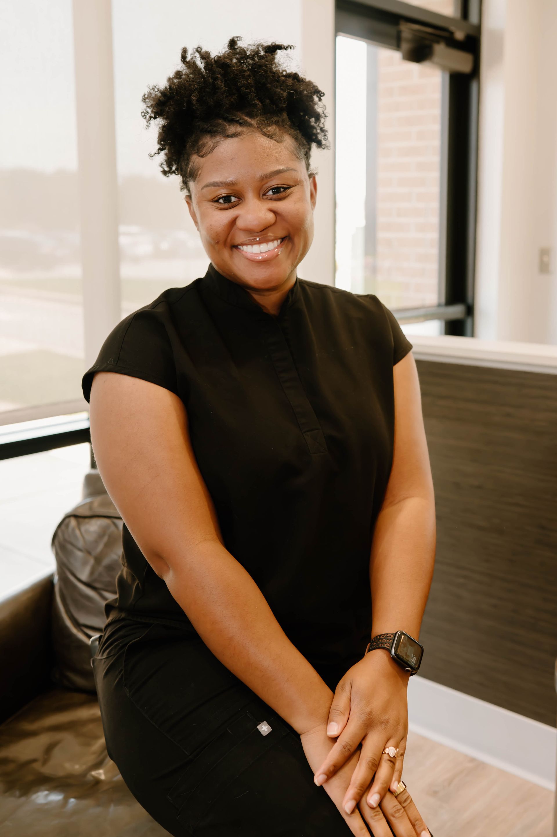 A woman wearing a black shirt and a watch is smiling
