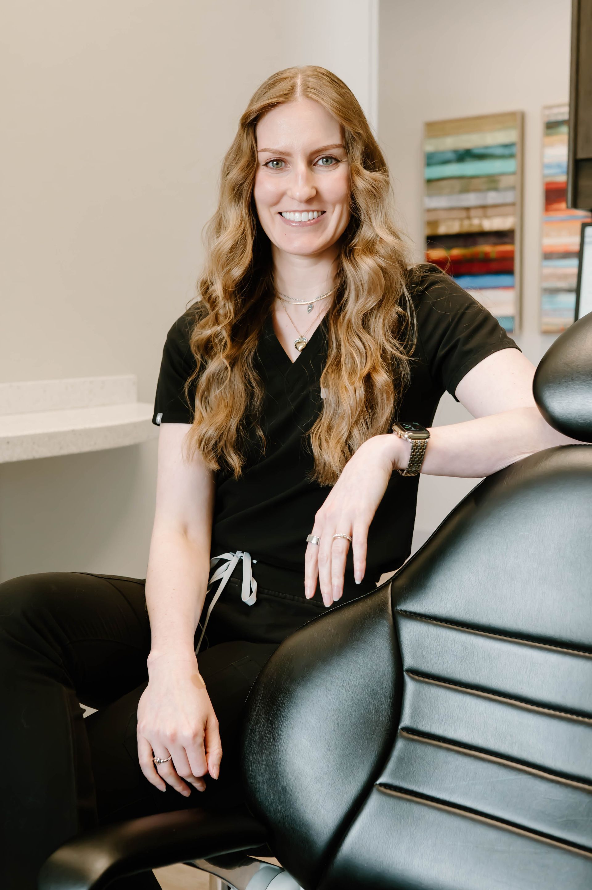 A woman in a black scrub top is smiling for the camera.