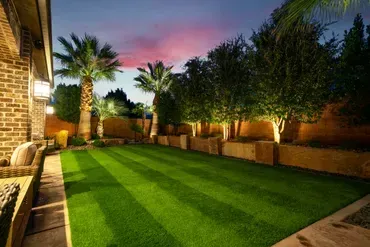 Green lawn with striped mowing pattern, palm trees, and evening lighting.
