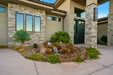 Exterior of a house with stone accents, a water feature, and landscaping.