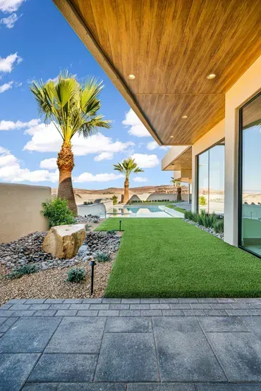Exterior view with lawn, palm trees, and modern home under a bright blue sky.