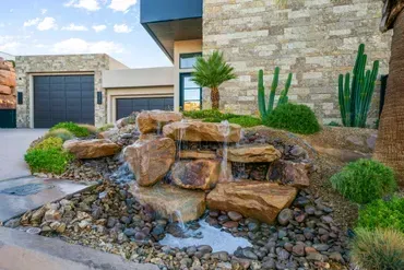 Water feature in front yard, cascading over rocks with desert landscaping, modern home.