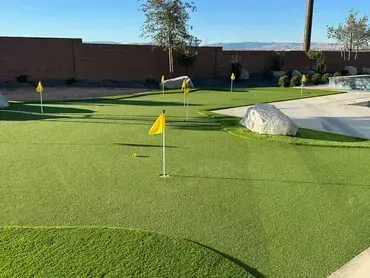 A putting green with several holes marked by yellow flags.