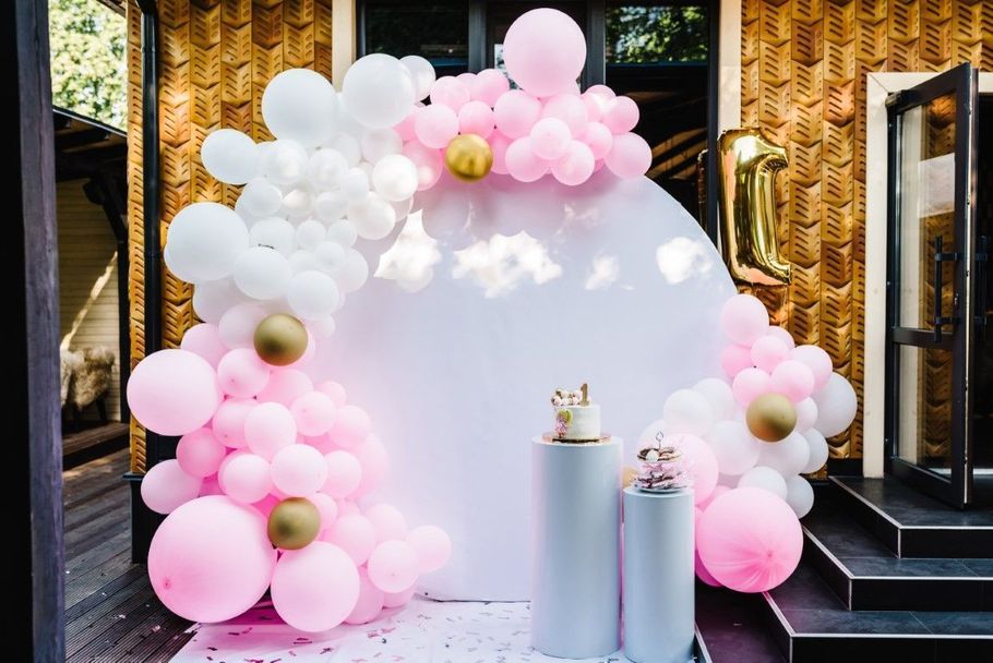 Pink and white balloon arch framing a small white display pedestal at an event entrance