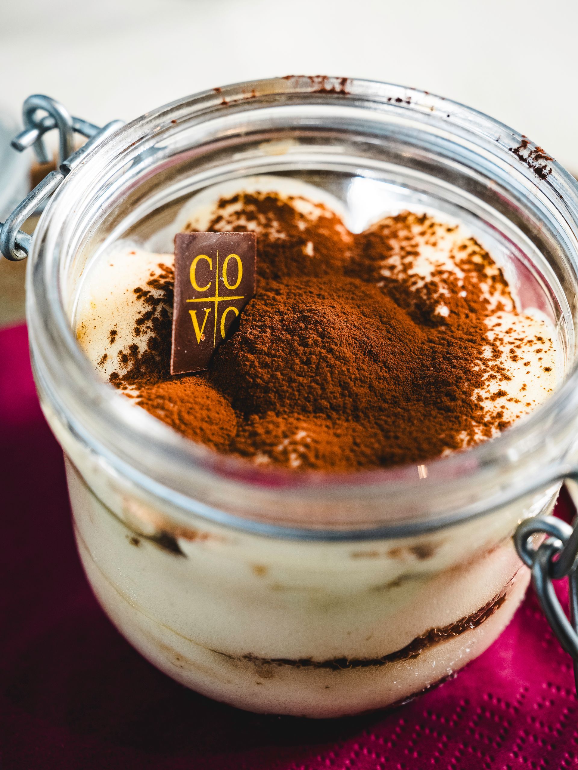Dessert tiramisù in un barattolo di vetro, guarnito con cacao in polvere