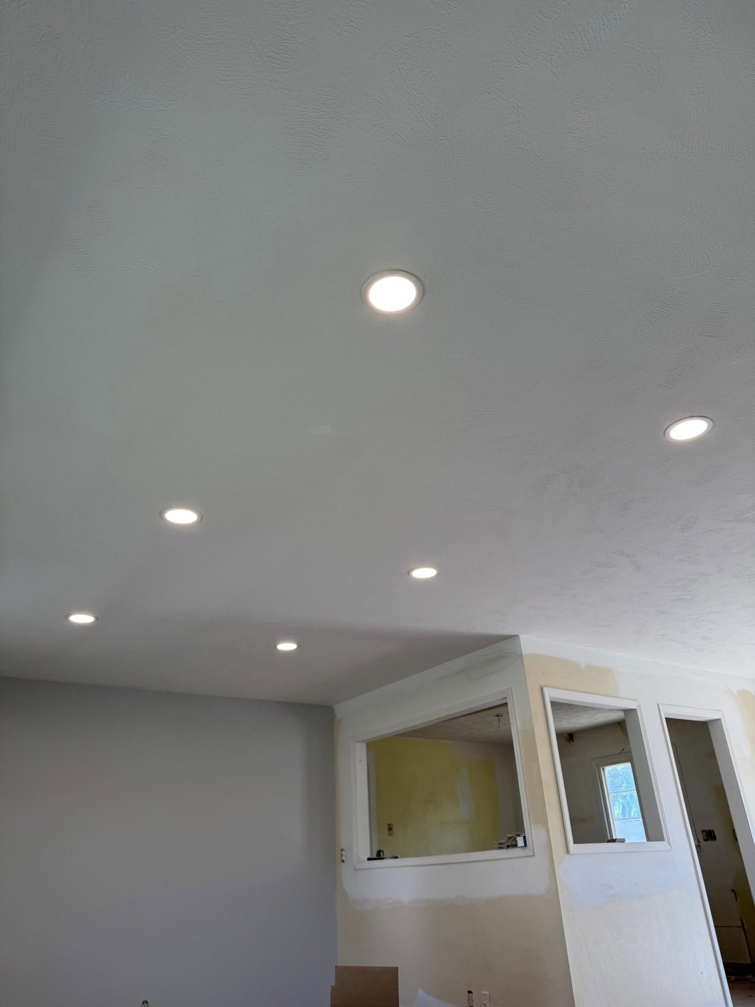 White ceiling with recessed lights above a room partition and door in a gray interior