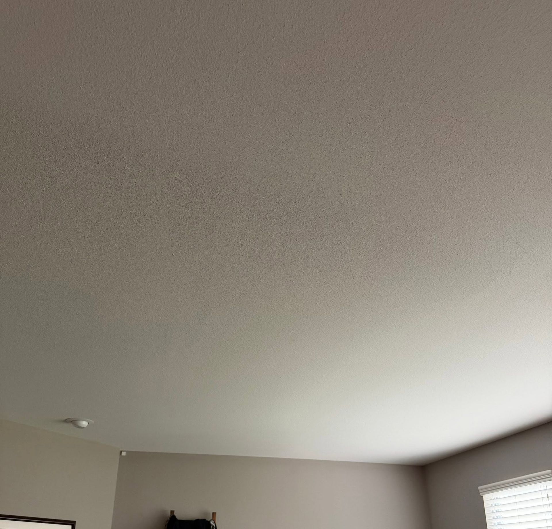 Ceiling and upper walls of a room, with a window on the right and part of a cabinet below.