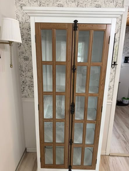 Wooden French doors with glass panes and a black bar latch in a white-framed doorway