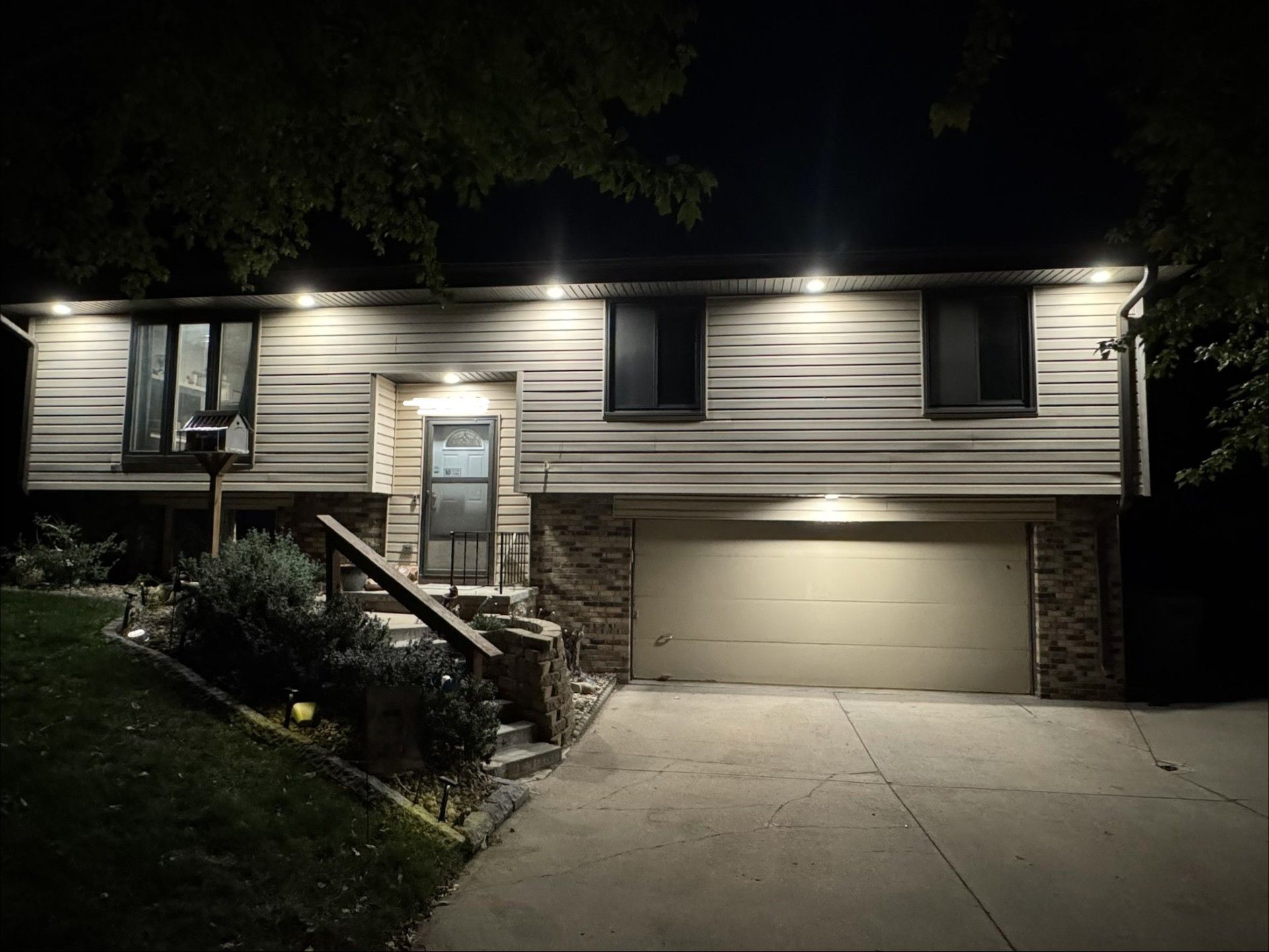Two-story house at night with lit porch, front stairs, and two-car garage.