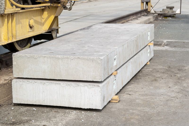 Two rectangular concrete slabs stacked outdoors near yellow machinery.