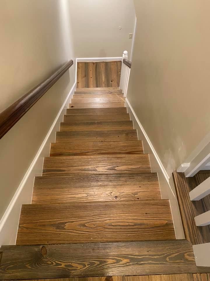 Wooden staircase with beige walls and a handrail, descending to a lower level.