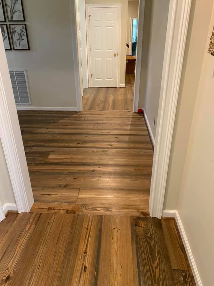Wooden hallway with light walls and white doors, viewed from one room into another.