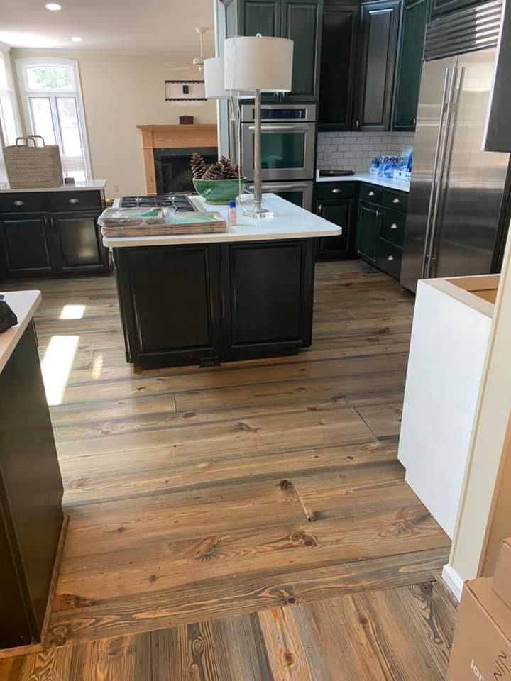 Modern kitchen with dark cabinets, stainless steel fridge, island, and wood flooring