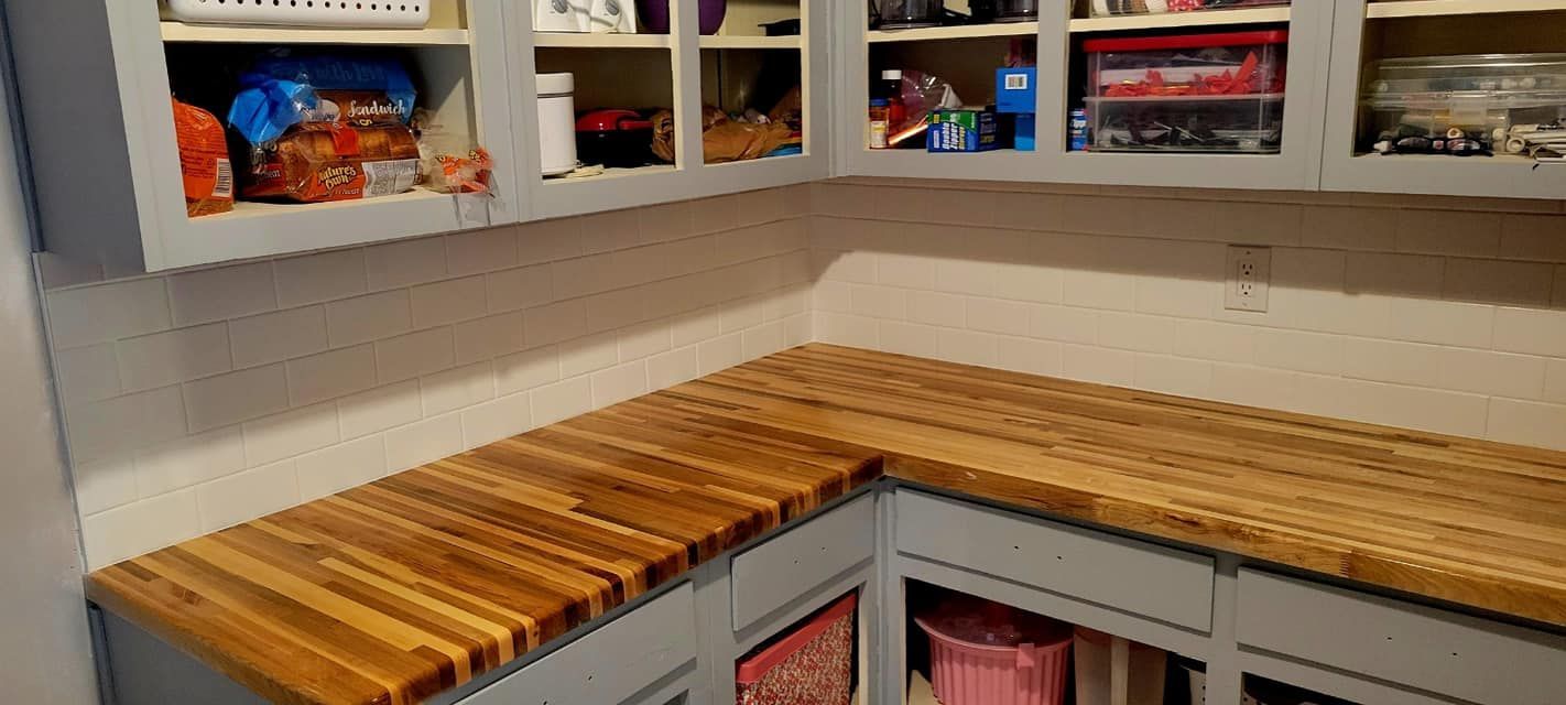 Kitchen corner with wooden countertop, open shelves, and cabinets containing food items