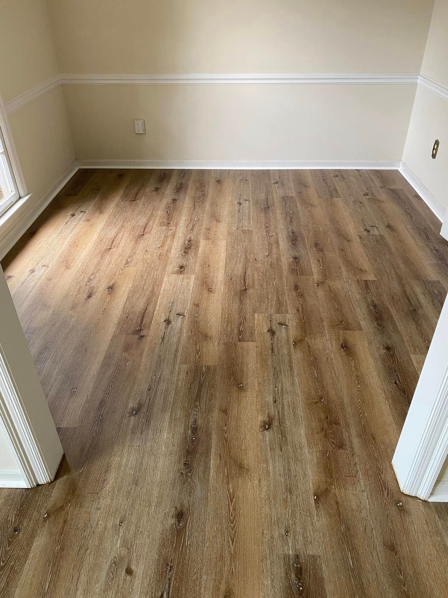 Empty room with light walls and wood-look flooring, viewed through a doorway.
