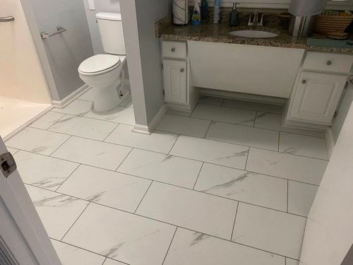 Empty bathroom with white tile floor, toilet, and vanity sink.