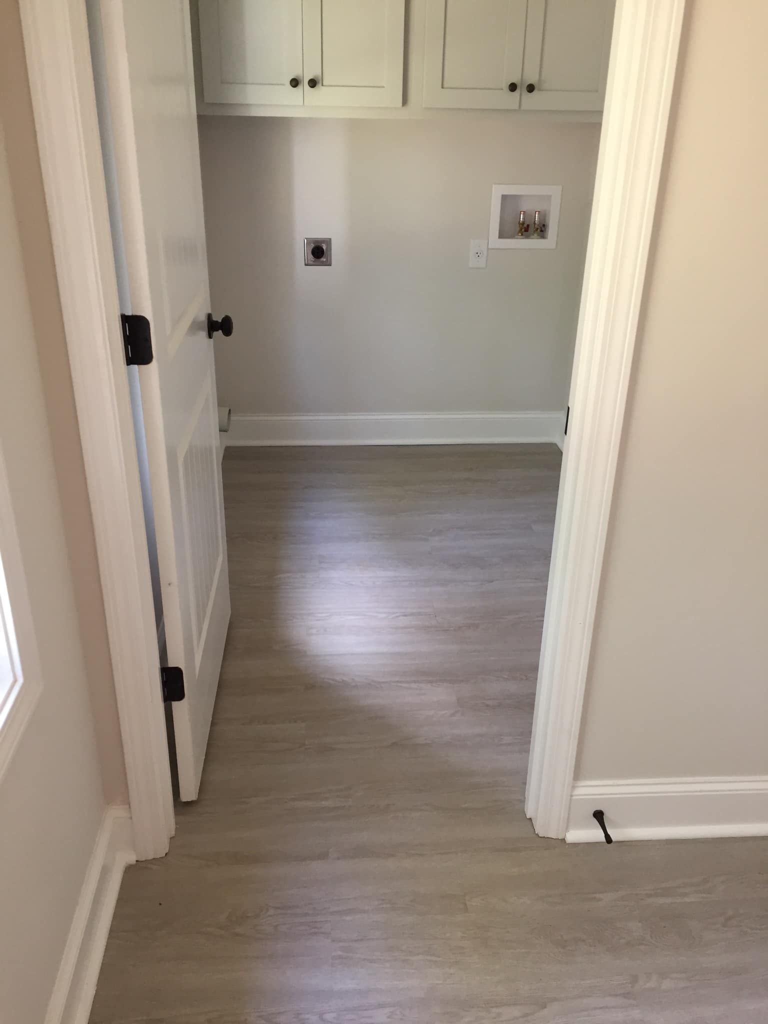 Empty hallway with light wood floor, white trim, and built-in cabinets at the end.