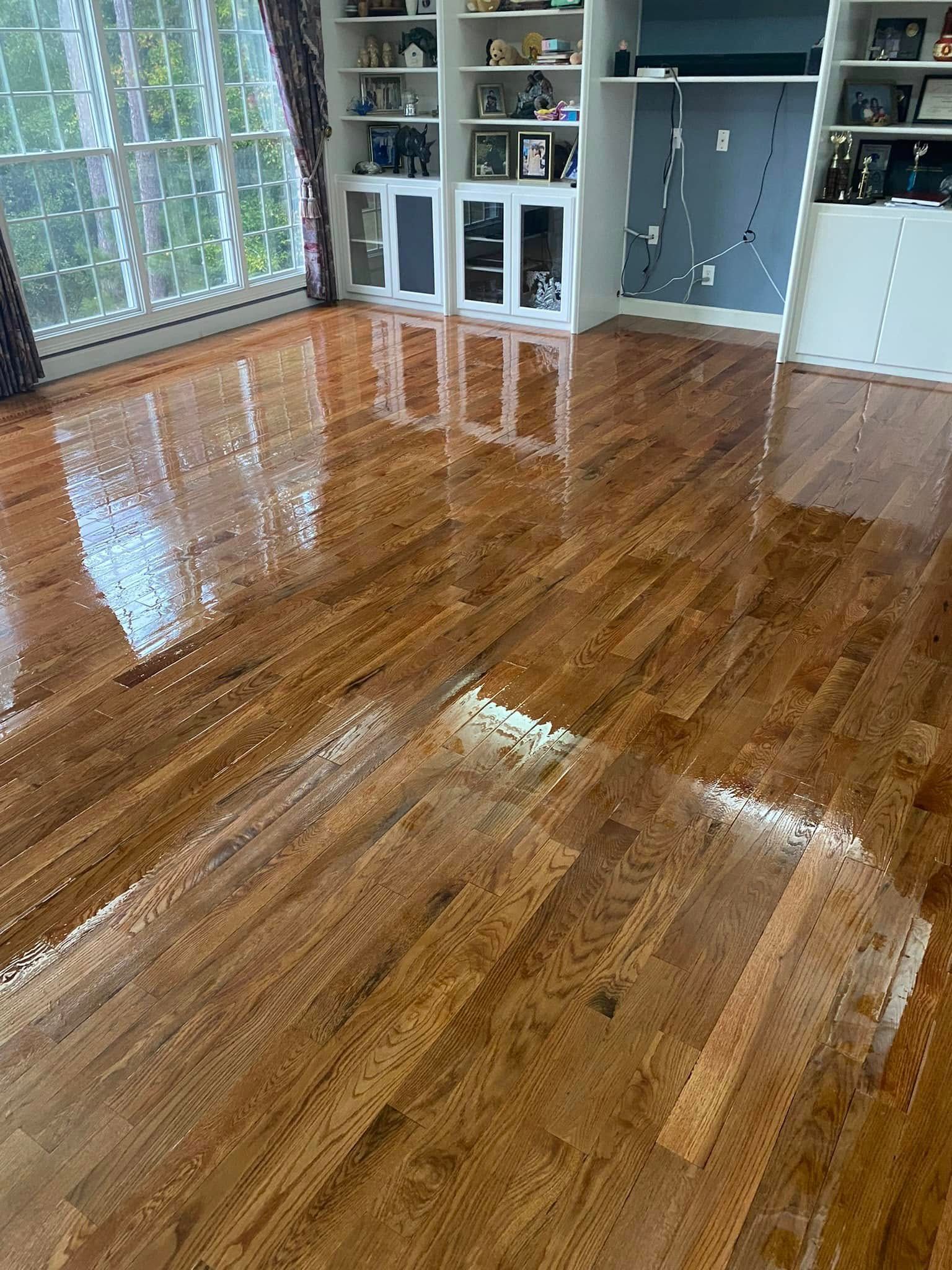 Glossy hardwood floor in a sunlit living room with built-in cabinets and glass doors