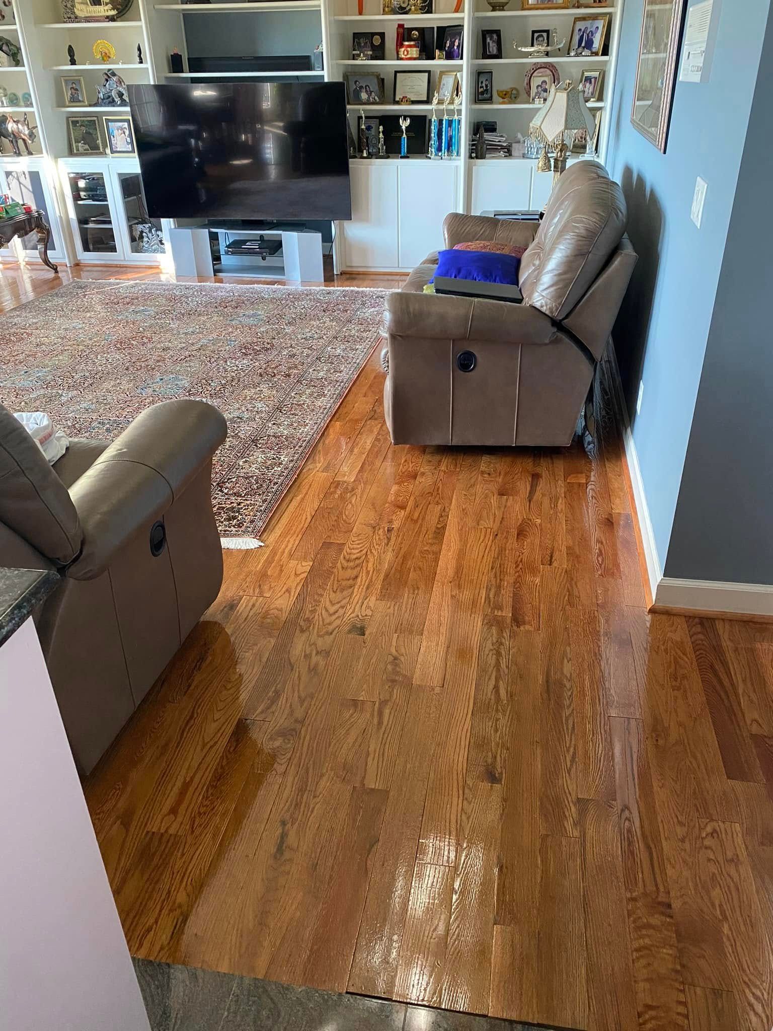 Living room with recliners, TV, shelves, and a hardwood floor runner leading to a rug.