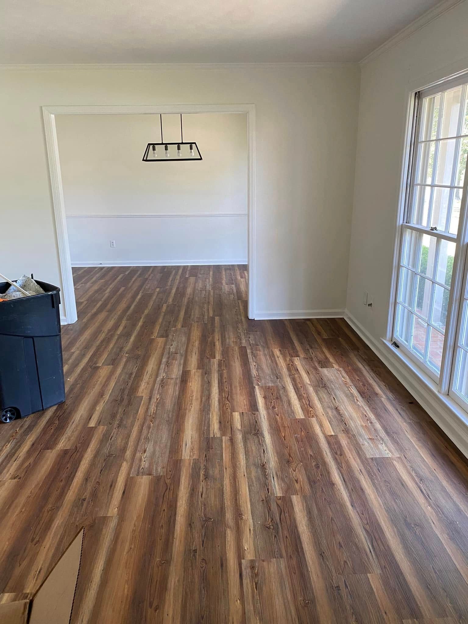 Empty room with wood floors, white walls, and a large window letting in light