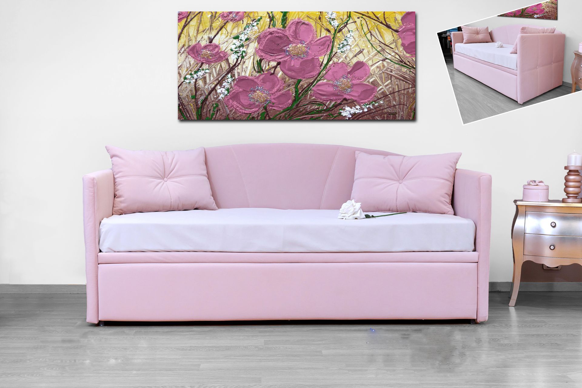 C'è un divano rosa in una stanza con un dipinto sulla parete sopra di esso.