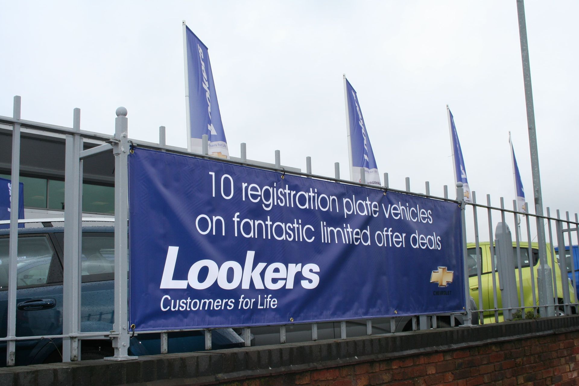 Blue banner for Lookers car dealership, offering deals on ten registration plate vehicles, with flags.