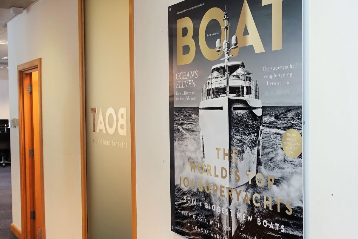 Poster and doorway in an office space. The word "BOAT" is visible on both. A yacht is pictured on the poster.