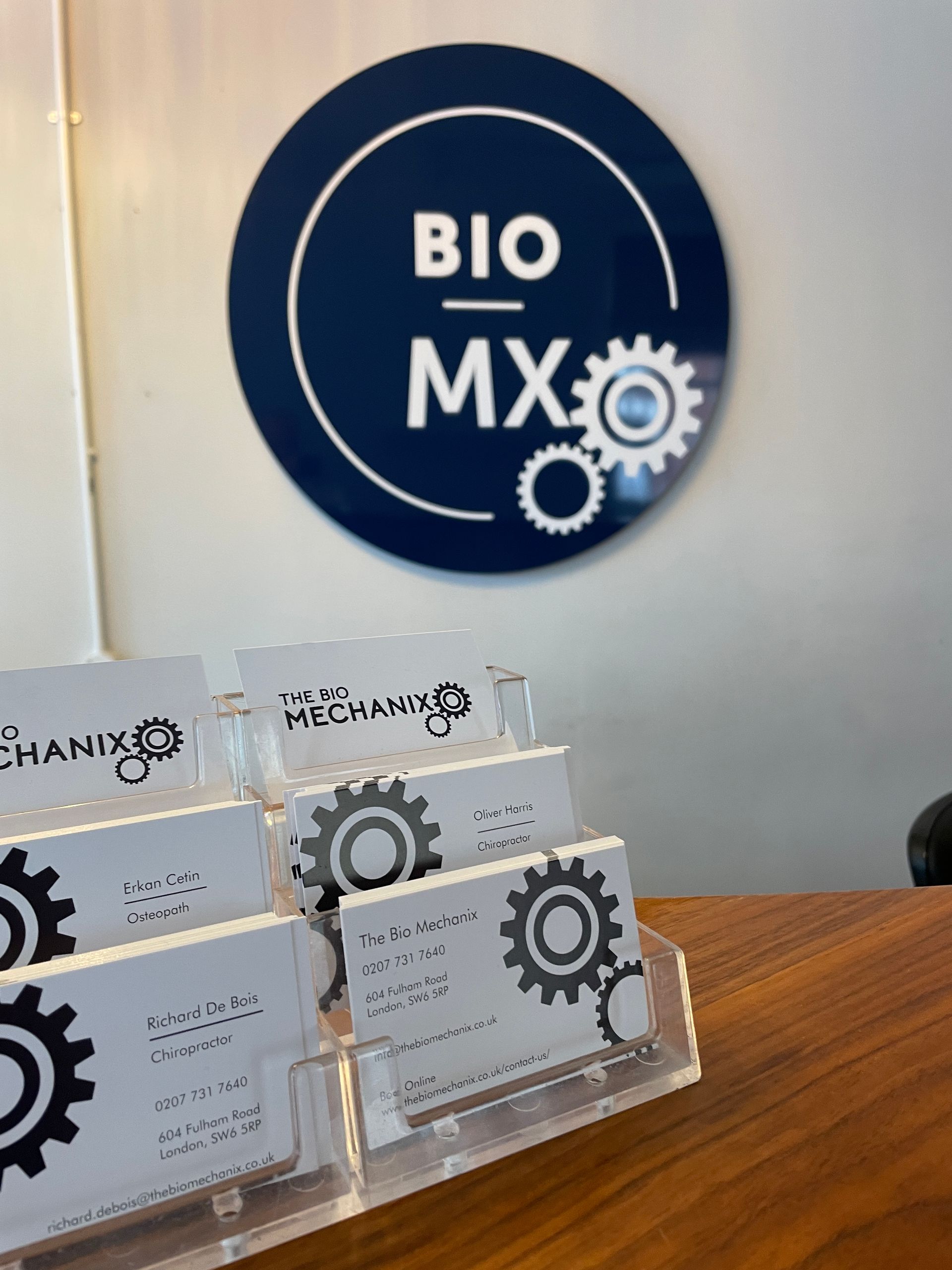 A business card holder with cards, a navy blue BIO MX sign with a gear graphic.