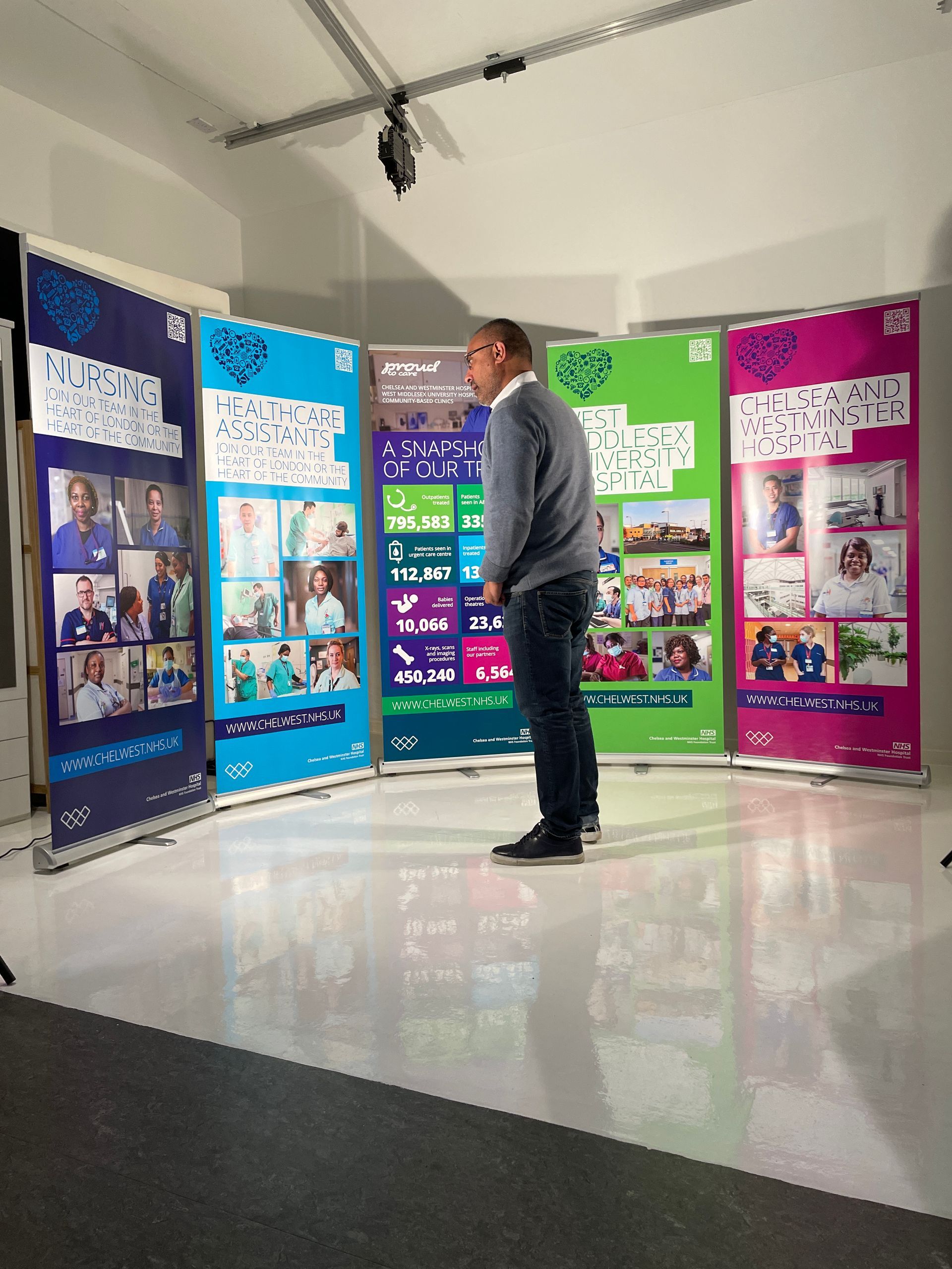 Man standing in front of multiple colorful roll-up banners in a brightly lit room.