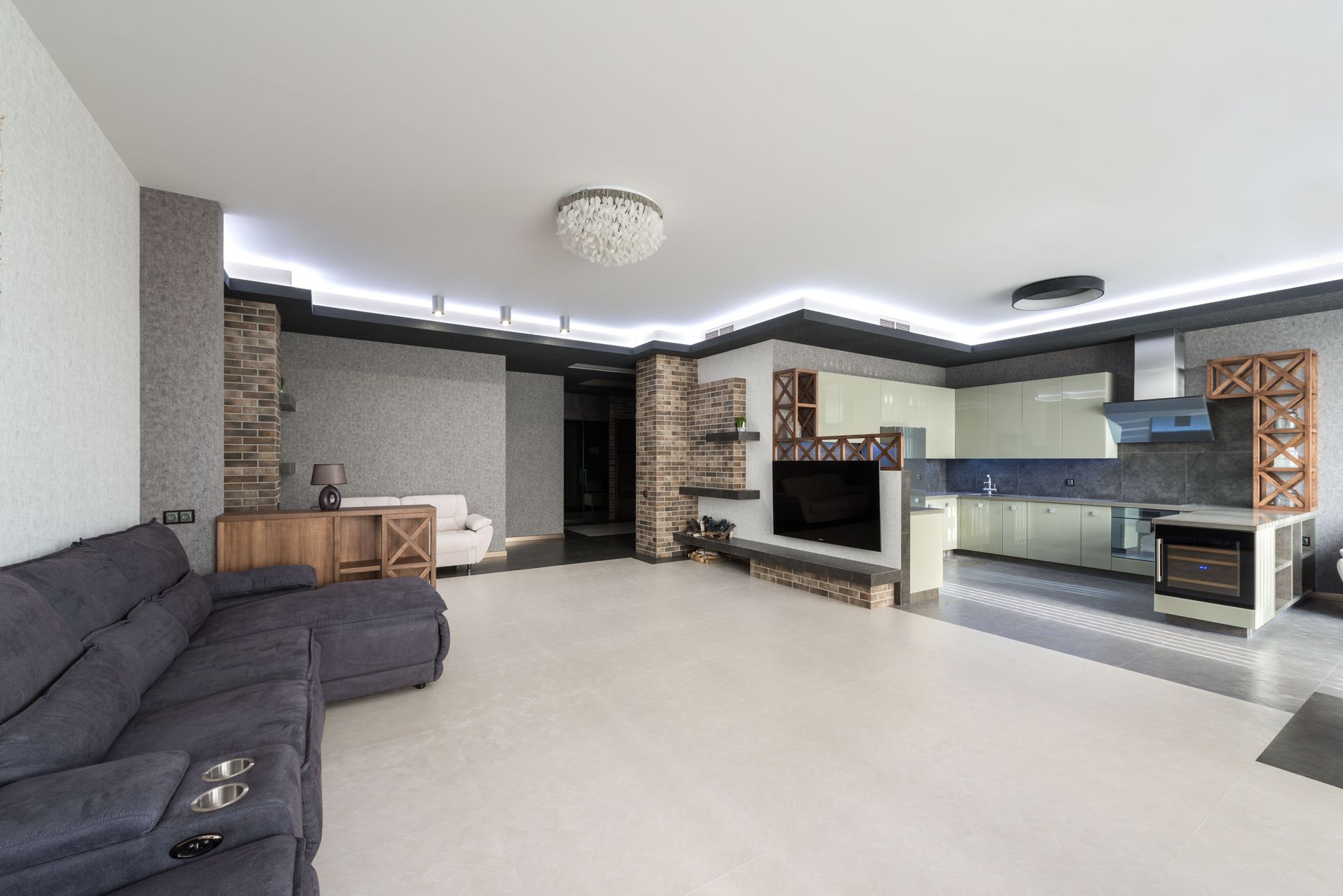 Modern living room with dark sectional sofa, stone fireplace, and open kitchen/bar area