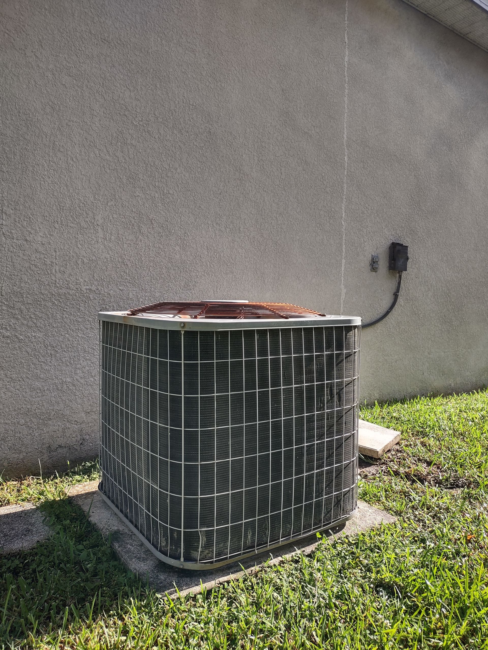 an air conditioner is sitting in the grass in front of a house .