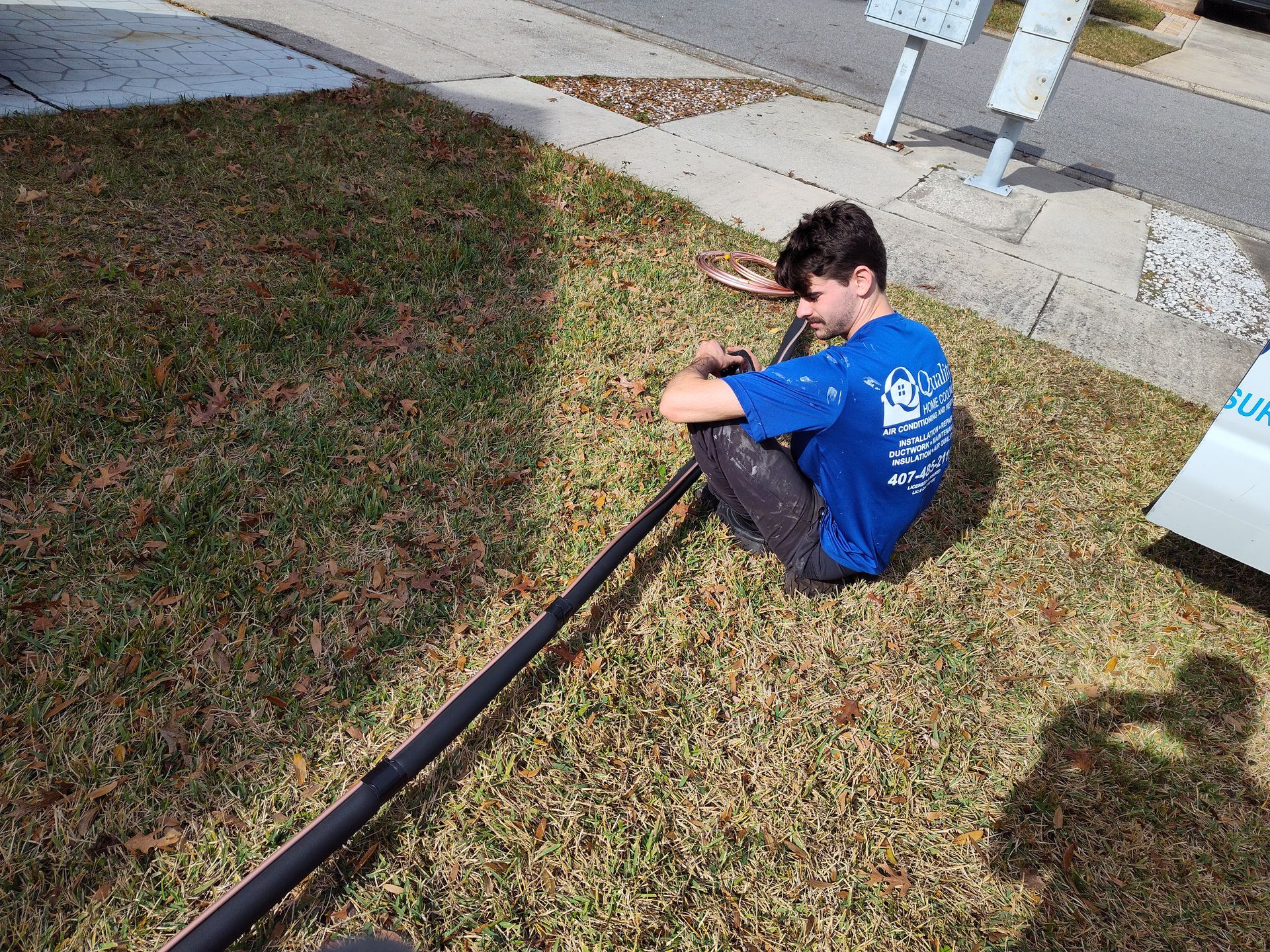 a man in a blue shirt is sitting on the grass with a hose .