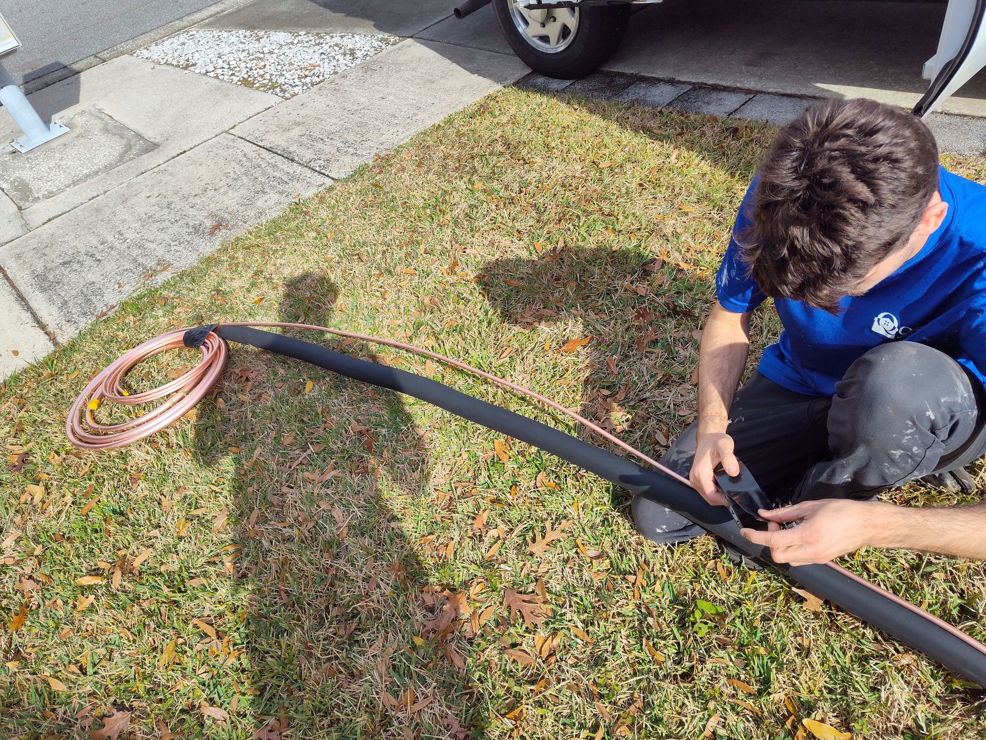 a man is kneeling on the grass working on a hose.