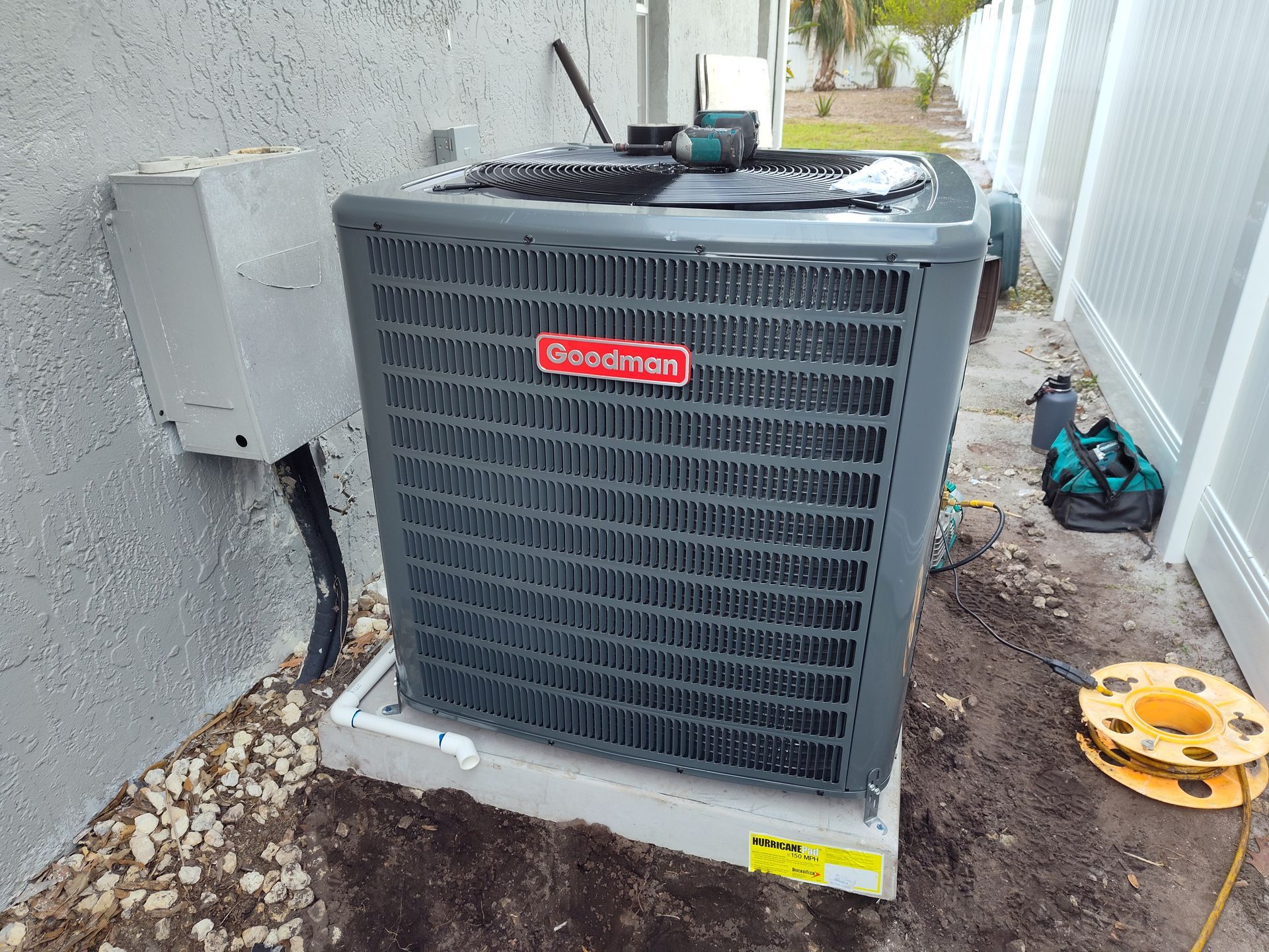 an air conditioner is sitting in the dirt next to a wall .