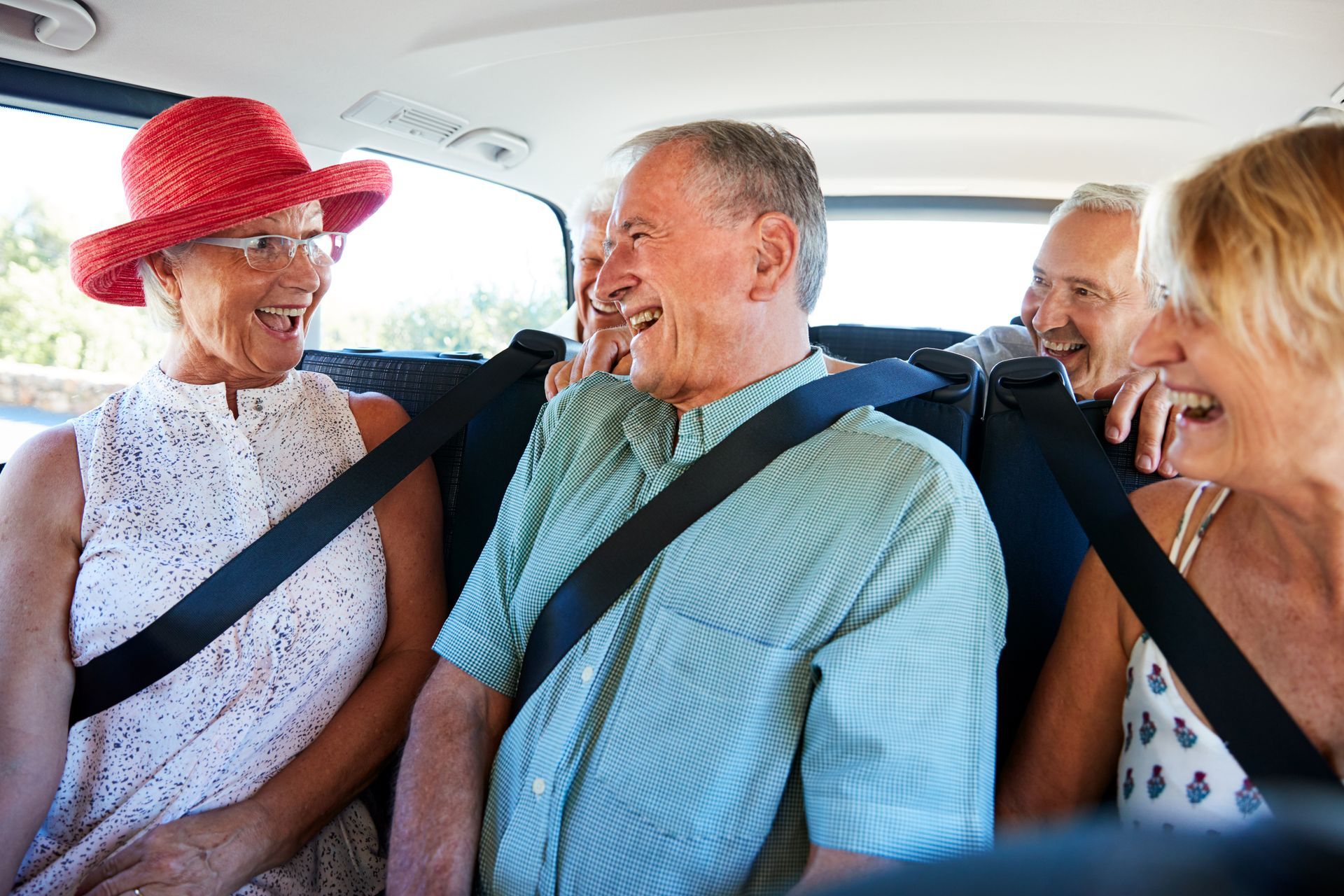 A group of happy senior friends sitting in a taxi being driven.