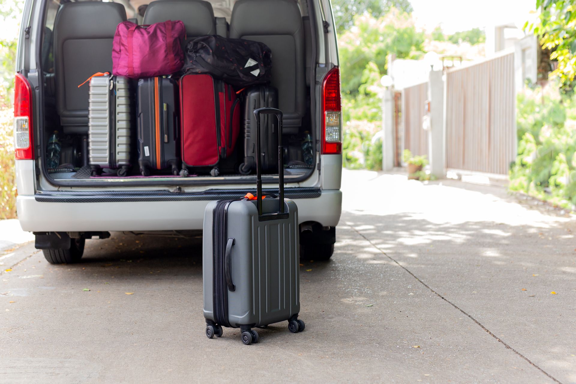 A maxi taxi with an opened rear door with carry-on luggage in the trunk. A maxi taxi with an opened rear door with carry-on luggage in the trunk.