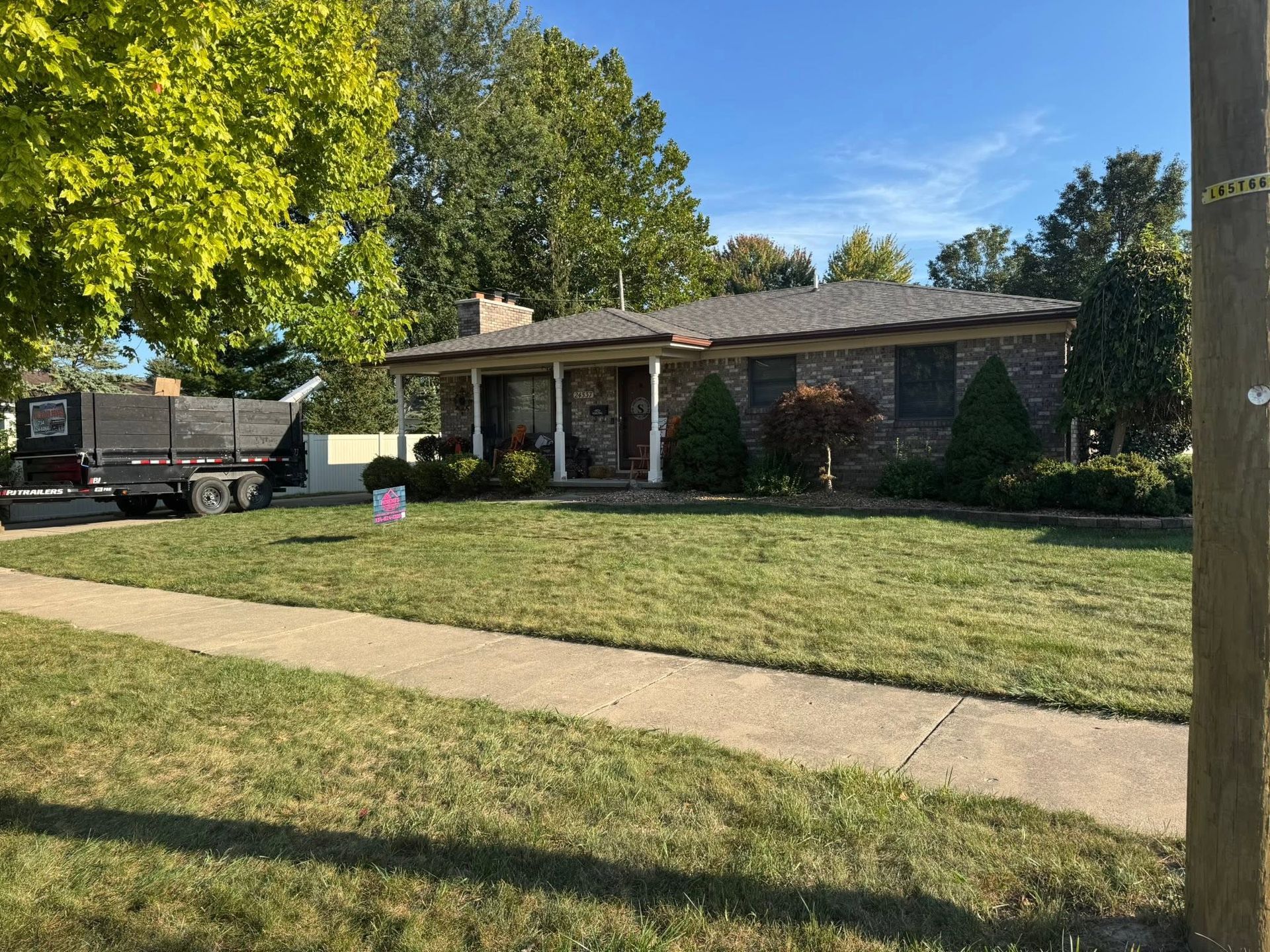 Single-story brick house with a front lawn, driveway, and parked truck on a sunny day