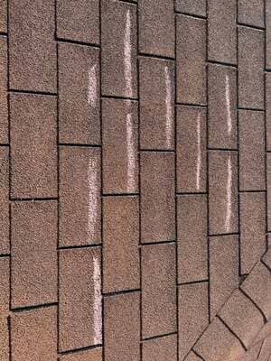 Close-up of brown shingle roofing with staggered vertical rows and a corner edge.