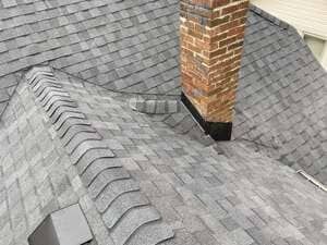 Gray shingled roof with a brick chimney and roof valley close-up