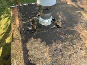 Rusted rooftop vent on a weathered, damaged roof