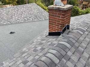 Gray shingle roof with a brick chimney and vent cap on a sloped rooftop