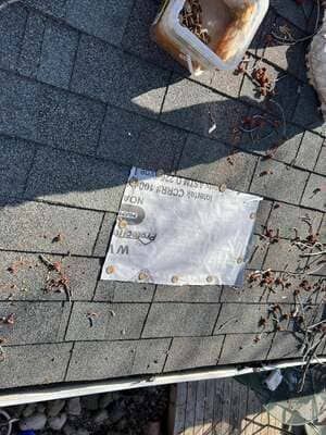 Paper sign and a rusted tray on gray pavement with scattered debris and cracks.