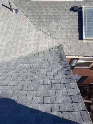 Roof shingles and dormer window on a house exterior, viewed from above.