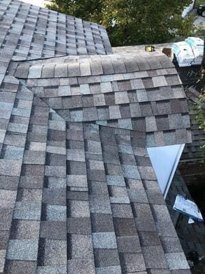 Damaged shingle roof with a large tear exposing the underlayment underneath