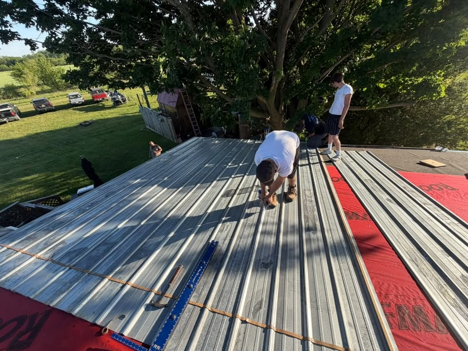 Metal roof under repair with tools and ladders near a chimney on a sunny day Metal roof under repair with tools and chimney on a sunny day